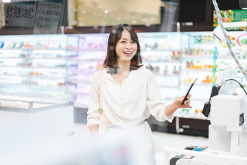 スーパーでスマホ決済を使う若い女性
