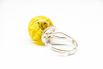 Back side of a yellow resin ring. Immortelle flowers in an epoxy resin sphere ball, silver colored base. Selective focus on the details, object isolated on white background.