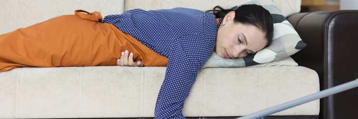 Tired woman lies on couch after cleaning apartment