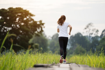 woman running on wooden path in field