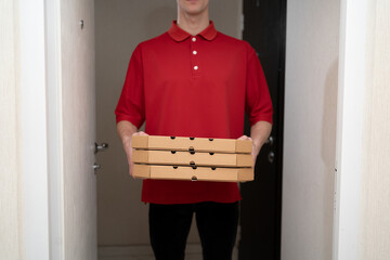 Pizza delivery courier man in red uniform, boxes from a pizzeria in the hands of a delivery man, delivery service