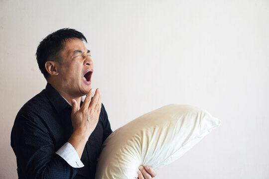 Asian Man Is Holding Pillow And Yawning. Concept : Sleepy Man. Go To Bed Late. Sleep Deprivation .    