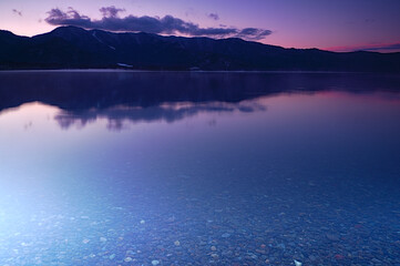 鮮やかな紫色のグラデーションの空のクリアな湖の夜明け。