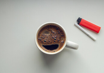 Simple morning coffee with cigarette and red lighter on white background. View from top.