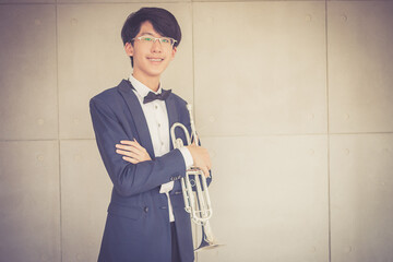 Portrait of young musician with suit form playing trumpet in music room.