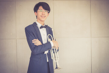 Portrait of young musician with suit form playing trumpet in music room. © Pornnarong