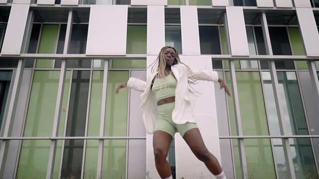 Stylish young African American woman dancing hip hop, street dance outdoors. Youth subculture.