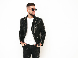 Fototapeta premium Portrait of handsome confident model. Sexy stylish man dressed in biker leather jacket and black jeans. Fashion hipster male isolated on white in studio. In sunglasses