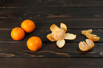 Whole orange tangerines and seen from peel with separate juicy slices, on wooden surface with copy space
