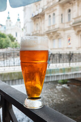 Drinking a draught blonde beer on a terrace from Karlovy Vary next to Tepla river. Travel to Czech...