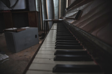 A beautiful perspective of the keys of an old abandoned piano. An ancient musical instrument. Black and white keys. Old abandoned interior.
