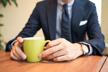 ビジネス用　カフェでコーヒーを飲むスーツの男性