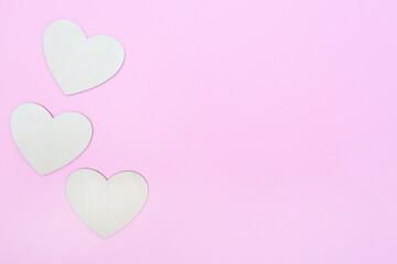 Fototapeta na wymiar Three hearts are made of wood on a pink background. Copy space. Place for text and logo. Valentine's Day. Flat lay
