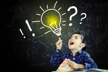 Cheerful schoolboy getting an idea in classroom