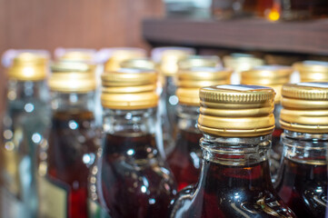 There are many small bottles of alcohol on the supermarket shelf. In the frame, the upper part of the bottles is the neck of the bottles and the cork. Selective focus