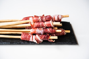 Slices of acorn-fed Iberian ham with breadsticks, Spanish tapa, for events, dinners or...