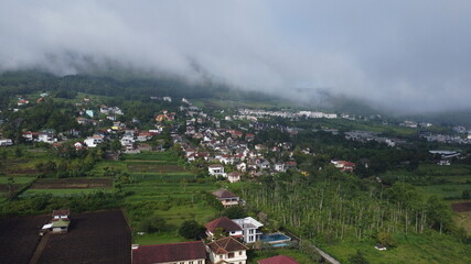 aerial photography of small city in mountains surrounded by morning fog, located in Batu, Indonesia