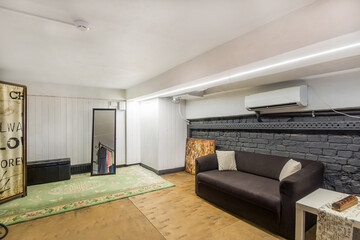 A simply decorated showroom room with a carpet, a fitting room, a mirror and a sofa.