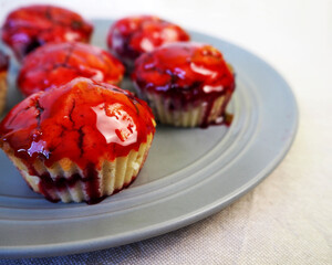 several gluten-free muffins with rice flour cherries, sprinkled with cherry red syrup, stand on a gray plate on a blue table. side view. gluten-free 
