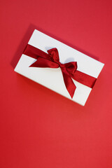 Valentines Day banner. White gift box with red ribbon on red background. Flat lay, top view. Love and romance concept.