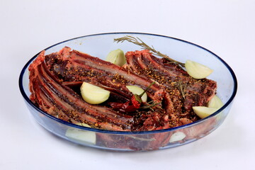 Marinated raw venison ribs with spices, onions and rosemary. Deer ribs in a bowl