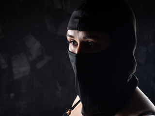Portrait of a girl in a black balaclava and a black bra.