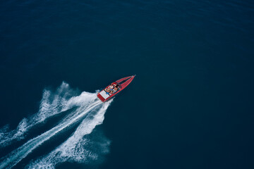 Fototapeta Red speed boat fast movement on the water top view. Travel - image. Top view of a red fast boat. Diagonal boat movement on blue water top view. obraz
