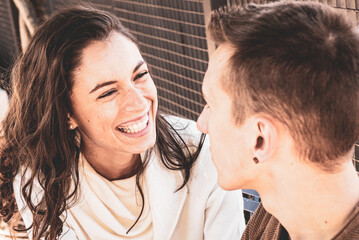couple moment of flirting, man talking and woman laughing, focus on the expression of the girl, warm filter, courtship, love and valentine's day concept