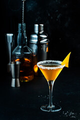 Sidecar cocktail with cognac, liqueur, lemon juice and ice. Black background, bar tools, copy space