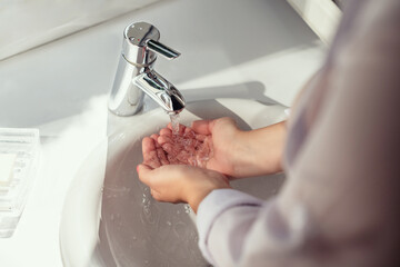 Woman washing hands under the water stream of the tap without soap. Hygiene concept. Top view