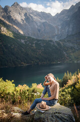 Fototapeta premium Young woman on a hiking trip sitting on a rock