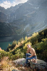 Fototapeta na wymiar Young woman on a hiking trip sitting on a rock