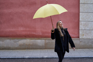 pretty girl plays in the street with her yellow umbrella