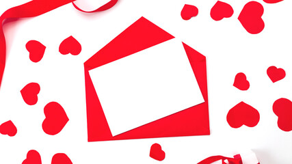The minimum layout of a letter with an red envelope on a white background is next to paper hearts. Invitation. Valentine's day. copy space. Flat lay, top view.