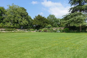 landscape garden with a grass lawn, flower beds and leafy green trees