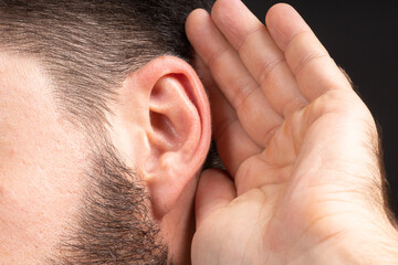 Macro ear of man with palm eavesdropping on secret information or secrets. Concept of foreign spy...