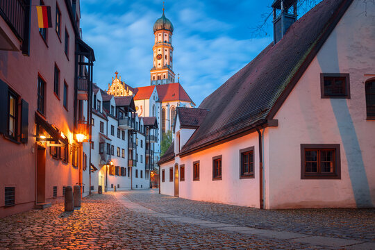 Augsburg, Germany. Cityscape image of old town street of Augsburg, Germany with the Basilica of St. Ulrich and Afra at autumn sunset.