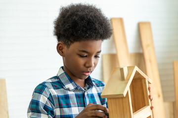 African black boy child kid carpenter sanding wood with sandpaper in carpentry workshop. Concept hobby at home.