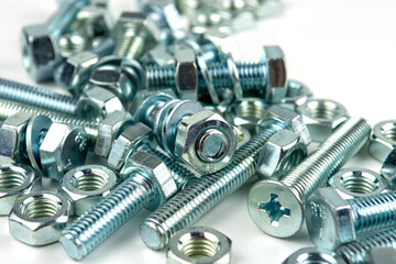 A large group of silver fasteners for fastening structures. Bolts and nuts with washers close-up on a white background.