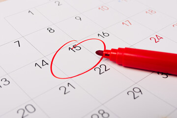 Calendar page with red pen close up. Focus on number 15 in calendar and empty red circle for design...