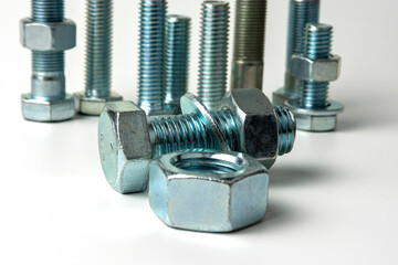 Several large silver metal bolts. Bolts, nuts and washers on a white background close up