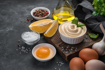 Homemade mayonnaise and ingredients on a dark background. Side view, copy space.