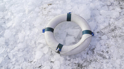 A lifebelt on the ice swimming spot at wintery beach and shards of ice