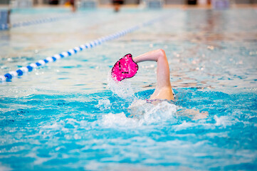 Swimmer trains in swimming pool using swimming equipment 