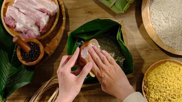 Front view of chef making Banh Chung with  pork rice and corn in wooden kitchen background