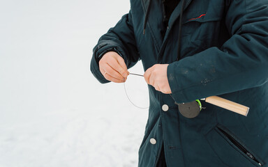 Close-up of man fisherman holding fishing rod, pulling line for winter fishing, outdoors