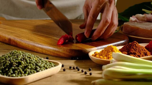 A Motion of chef cutting a onion in a wooden chopping board and ingredient in kitchen background