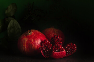Mysterious ambiance featuring ripe pomegranates, with one split revealing its ruby-like seeds,...