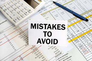 mistakes to be avoided are written on the white plate. Financial document and white calculator with a pen