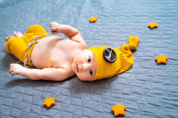 Newborn baby boy in suit on a grey background. In a hat.